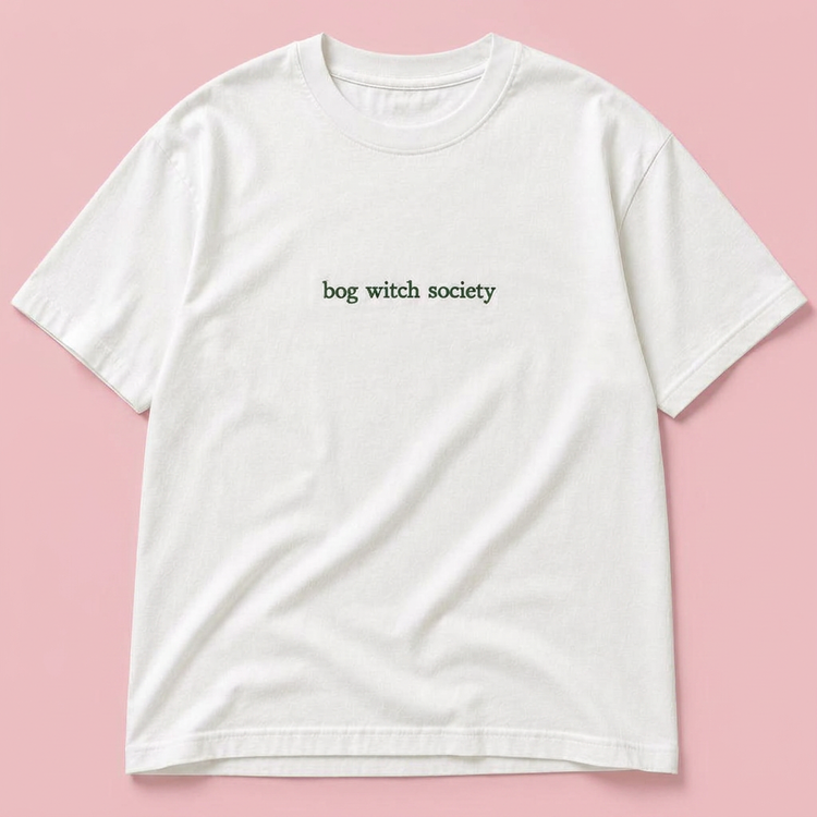 Bog Witch Society embroidered white t-shirt on a blush pink background